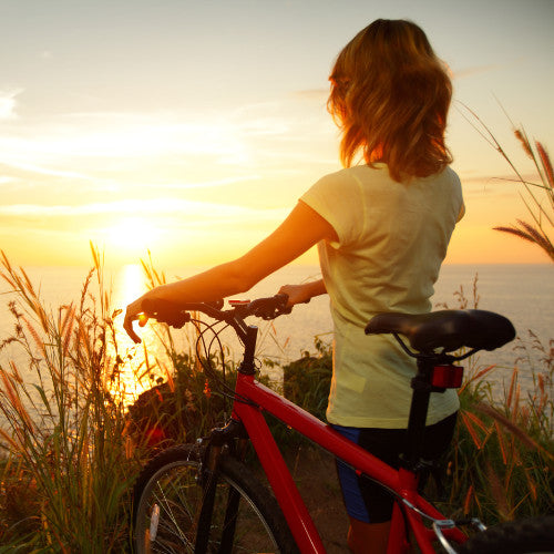 Woman with bike watching the sunset