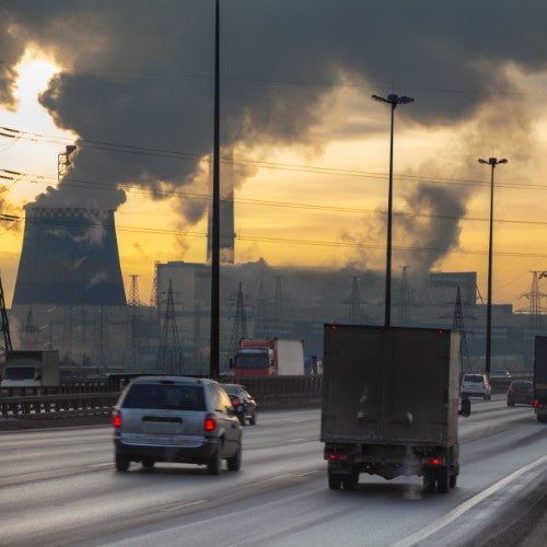 Cars driving past towers with billowing smoke