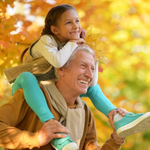 Man with a young girl on his shoulders smiling