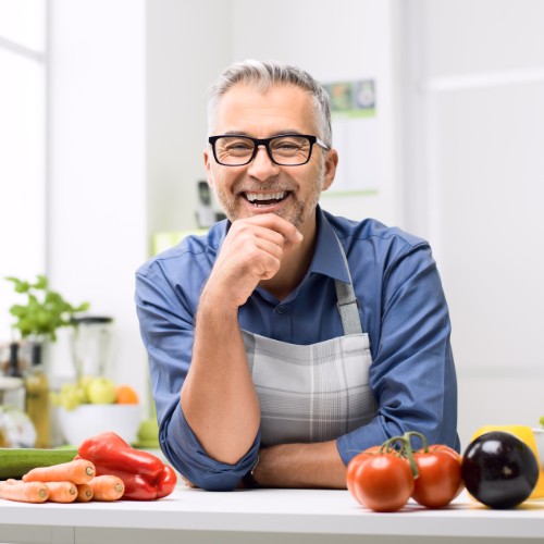 Smiling man in kitchen with fruit and vegetables