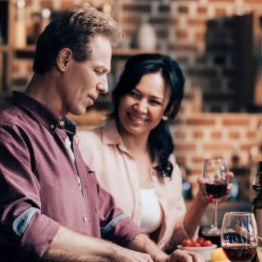 Man and woman cooking and drinking red wine