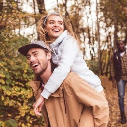 Man giving woman a donkey back smiling