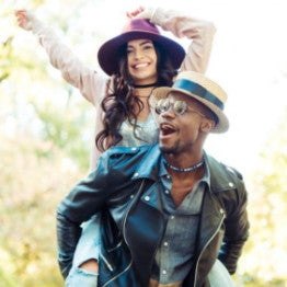 Man giving a woman a donkey back, both wearing hats and smiling