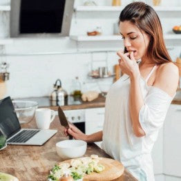 Woman tasting food from a chopping board