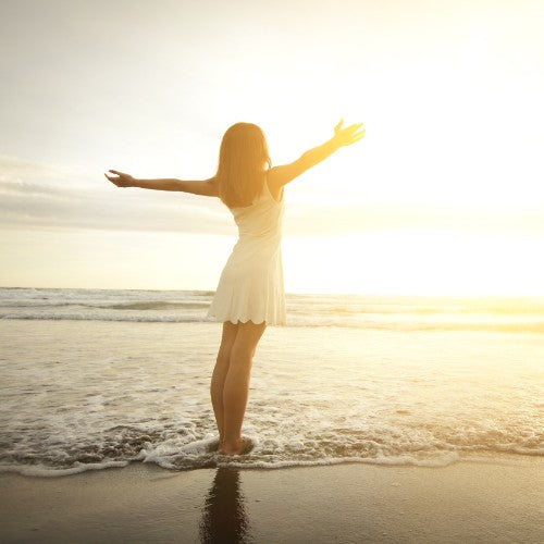 Woman stood in the sea looking at the sunset