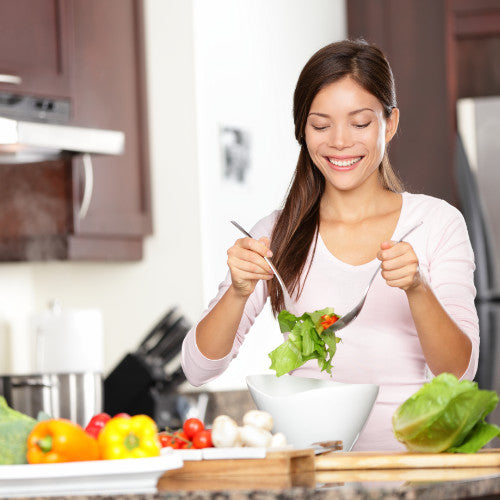 Woman tossing salad in a kitchen
