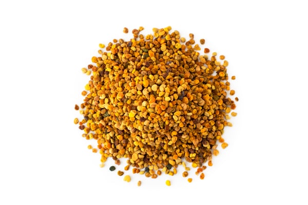 Pile of small, round, orange-brown bee pollen on a white background