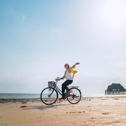 Woman cycling on the beach in the sun