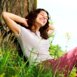 Smiling woman sat against a tree relaxing