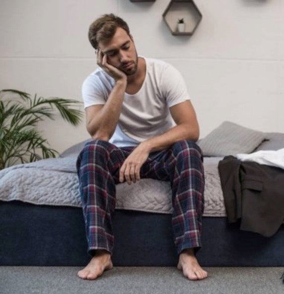 Man looking tired sat on a bed