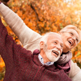 Older man and woman with arms outstretched and smiling